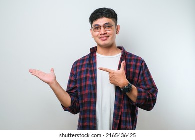 Young handsome asian man wearing casual shirt over white background with a big smile on face, pointing with hand finger to the side looking at the camera. - Shutterstock ID 2165436425