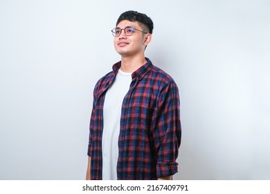 Young Handsome Asian Man Wearing Casual Shirt Over Isolated White Background Looking Away To Side With Smile On Face, Natural Expression. Laughing Confident.