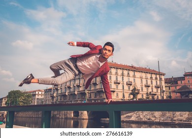 Young handsome Asian model dressed in red blazer jumping a balustrade