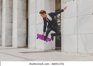 Young handsome Asian model dressed in dark suit and tie jumping with his skateboard - Powered by Shutterstock