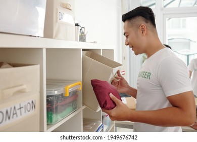 Young Handsome Asian Volunteer Working At Office Of Charitable Foundation, He Is Checking Donation Boxes After Event