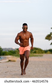 Young, Handsome, Athletic Muscular Black Guy Running Along Sandy Beach. Man Fitness Model With A Beautiful Body.