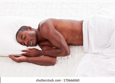 Young handsome Athletic muscular ethnic black Afro-American man resting in bed