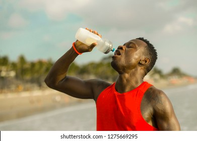 young handsome and attractive black African American sport man tired and thirsty after running workout holding bottle drinking water or isotonic energy drink recovering in hydration concept - Powered by Shutterstock