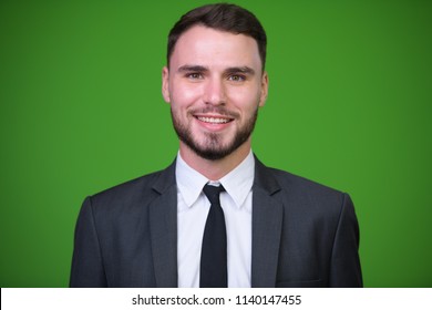 Young handsome bearded businessman against green background - Powered by Shutterstock