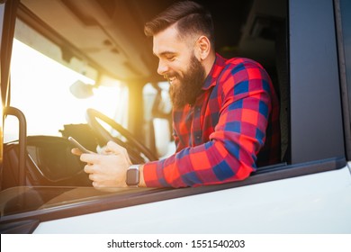 Young handsome bearded man using smart phone in his truck.
