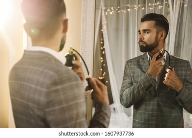 Young And Handsome Bearded Man Is Using Atomizer Nozzle With Perfume