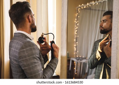 Young And Handsome Bearded Man Is Using Atomizer Nozzle With Perfume