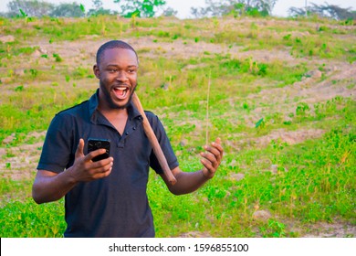 Young Handsome Black Farmer Standing In The Farm And Happy Over An Offer He Got On His Phone