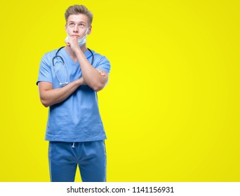 Young handsome blond doctor serious face thinking about question, very confused idea