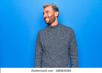 Young Handsome Blond Man Wearing Casual Sweater Standing Over Isolated Blue Background Looking To Side, Relax Profile Pose With Natural Face And Confident Smile.