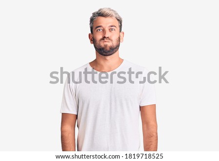 Young handsome blond man wearing casual t-shirt sticking tongue out happy with funny expression. emotion concept. 