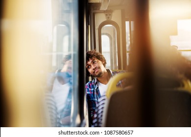 A Young Handsome Bored Man Is Sitting In A Bus Seat Leaned And Looking Through The Window As He Waits For Arrival To His Destination.