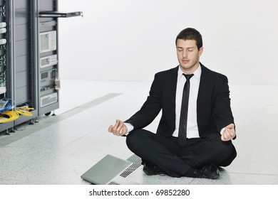 young handsome business man in black suit practice yoga and relax at network server room while representing stress control concept - Powered by Shutterstock