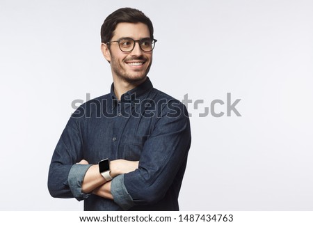 Young handsome business man dressed in casual denim shirt with smartwatch on wrist, isolated on gray background