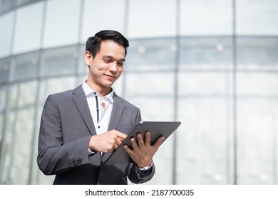 Young handsome business man holding a tablet looking away. - Shutterstock ID 2187700035