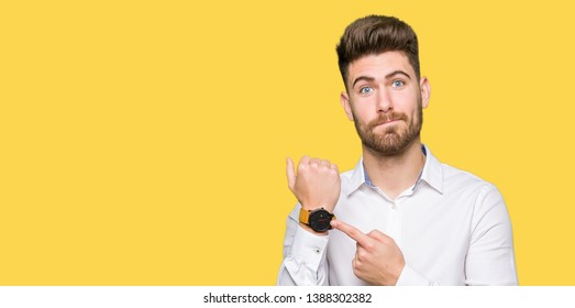 Young handsome business man In hurry pointing to watch time, impatience, upset and angry for deadline delay - Shutterstock ID 1388302382