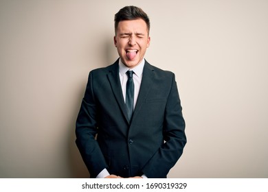 Young handsome business man wearing elegant suit and tie over isolated background sticking tongue out happy with funny expression. Emotion concept. - Shutterstock ID 1690319329