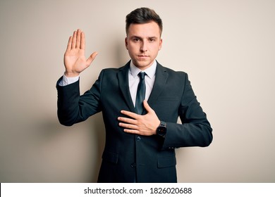 Young handsome business man wearing elegant suit and tie over isolated background Swearing with hand on chest and open palm, making a loyalty promise oath