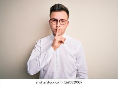 Young Handsome Business Mas Wearing Glasses And Elegant Shirt Over Isolated Background Asking To Be Quiet With Finger On Lips. Silence And Secret Concept.