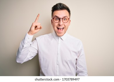 Young Handsome Business Mas Wearing Glasses And Elegant Shirt Over Isolated Background Pointing Finger Up With Successful Idea. Exited And Happy. Number One.