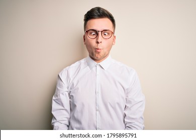 Young Handsome Business Mas Wearing Glasses And Elegant Shirt Over Isolated Background Making Fish Face With Lips, Crazy And Comical Gesture. Funny Expression.