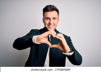 Young Handsome Business Mas Wearing Elegant Winter Coat Standing Over Isolated Background Smiling In Love Doing Heart Symbol Shape With Hands. Romantic Concept.