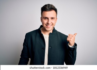 Young Handsome Business Mas Wearing Elegant Winter Coat Standing Over Isolated Background Smiling With Happy Face Looking And Pointing To The Side With Thumb Up.