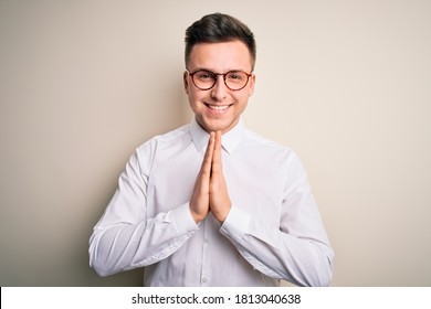 Young Handsome Business Mas Wearing Glasses And Elegant Shirt Over Isolated Background Praying With Hands Together Asking For Forgiveness Smiling Confident.