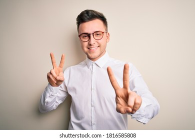 Young Handsome Business Mas Wearing Glasses And Elegant Shirt Over Isolated Background Smiling Looking To The Camera Showing Fingers Doing Victory Sign. Number Two.