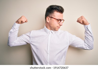 Young Handsome Business Mas Wearing Glasses And Elegant Shirt Over Isolated Background Showing Arms Muscles Smiling Proud. Fitness Concept.