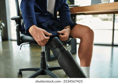 A young, handsome businessman with a disability adjusts his clothing while sitting in a contemporary office. - Powered by Shutterstock