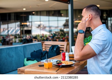 Young Handsome Businessman Eating In A Restaurant While Using Airpods