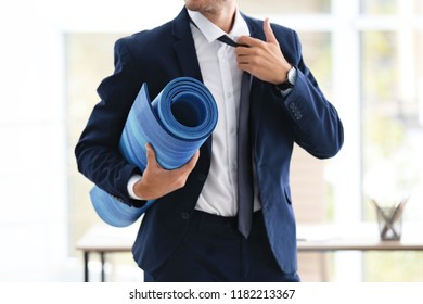 Young Handsome Businessman Holding Yoga Mat In Office. Gym After Work