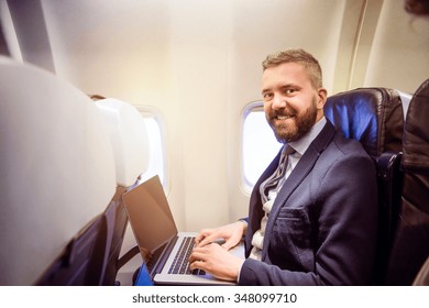 Young Handsome Businessman With Notebook Sitting Inside An Airplane