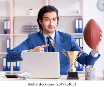 Young handsome businessman with rugby ball in the office - Powered by Shutterstock