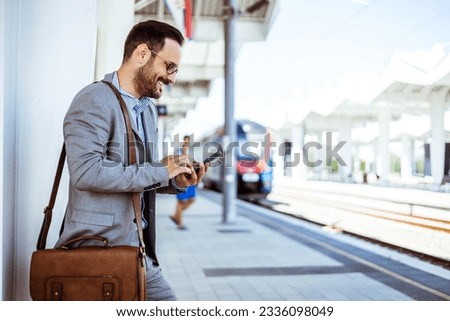 Young handsome businessman with smart phone in subway. Close up of a young businessman using his phone at a railroad station. Businessman using mobile phone at train station