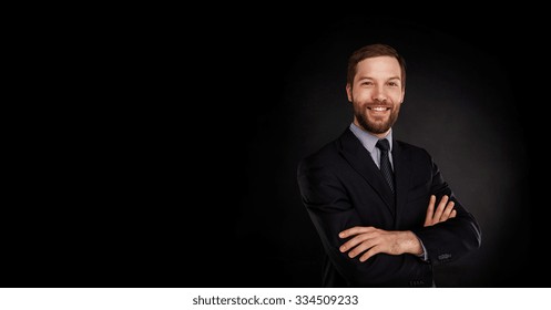Young handsome businessman in a suit with great smile against black background with lots of copy space