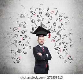 Young handsome businessman is thinking about education at business school. Drawn business icons over the concrete wall. Graduation hat. - Powered by Shutterstock
