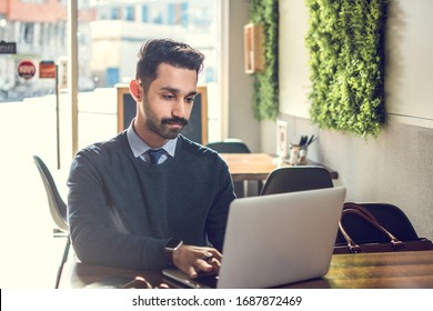 Young handsome Businessman working on laptop in cafe.