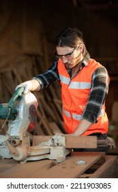 Young And Handsome Caucasian Carpenter Craftsman In Carpentry Shop Wearing Safety Uniform Workwear Use Circular Saws To Cut Wood Board To Make Furniture. Small Business And Freelance Craftsman