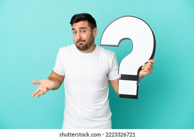 Young handsome caucasian man isolated on blue background holding a question mark icon and having doubts - Powered by Shutterstock