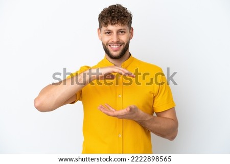 Young handsome caucasian man isolated on white background holding copyspace imaginary on the palm to insert an ad