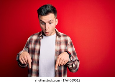 Young Handsome Caucasian Man Wearing Casual Modern Shirt Over Red Isolated Background Pointing Down With Fingers Showing Advertisement, Surprised Face And Open Mouth