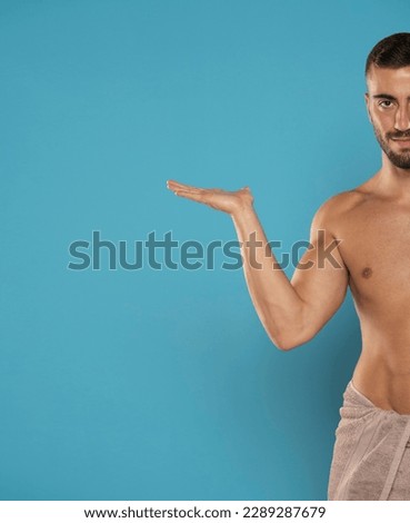 Young handsome caucasian shirtless man over isolated blue studio background holding copyspace imaginary on the palm to insert an ad