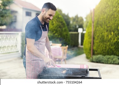 Young Handsome Chef Smiling And Cleaning Grill