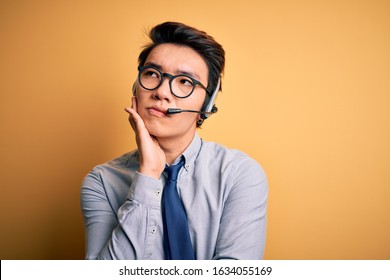 Young Handsome Chinese Call Center Agent Man Wering Glasses Using Headset Thinking Looking Tired And Bored With Depression Problems With Crossed Arms.