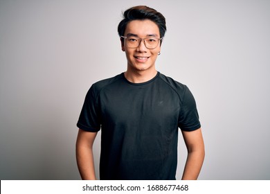 Young Handsome Chinese Man Wearing Black T-shirt And Glasses Over White Background With A Happy And Cool Smile On Face. Lucky Person.