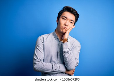 Young Handsome Chinese Man Wearing Casual Shirt Standing Over Isolated Blue Background Thinking Looking Tired And Bored With Depression Problems With Crossed Arms.