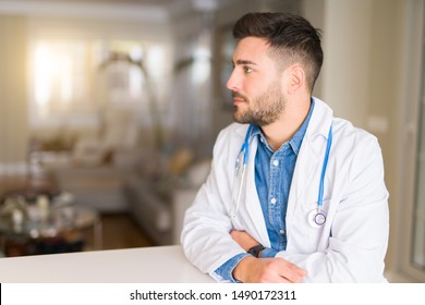 Young Handsome Doctor Man At The Clinic Looking To Side, Relax Profile Pose With Natural Face With Confident Smile.